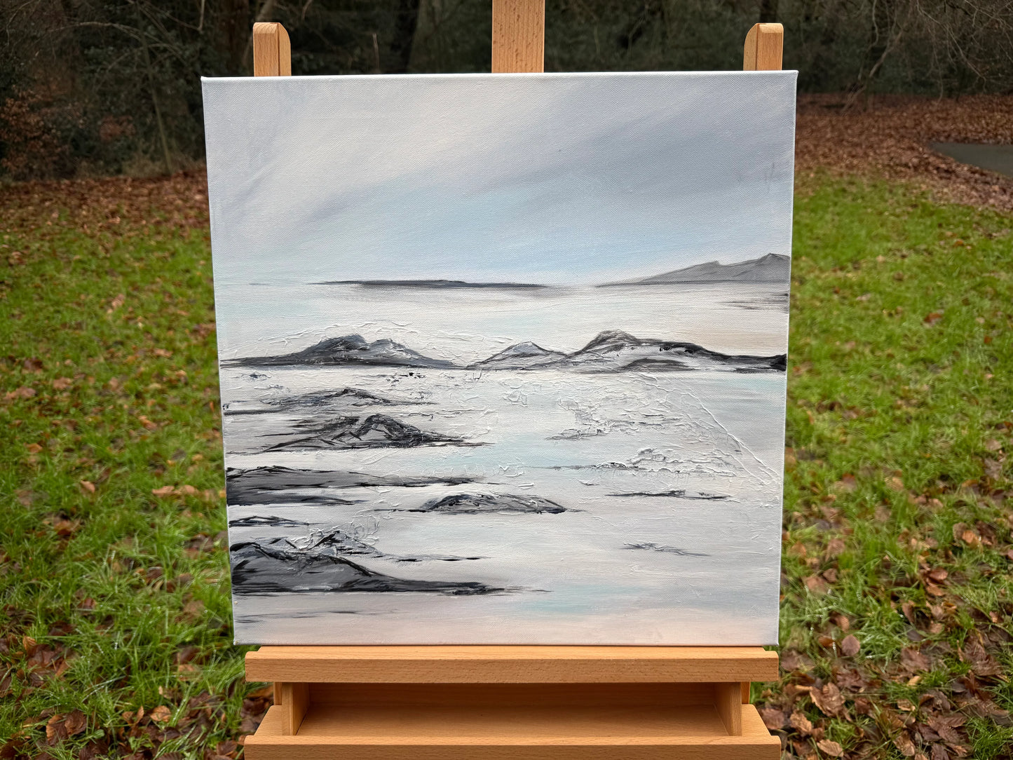 Textured abstract landscape oil painting with soft blue and gray tones on canvas, displayed outdoors.