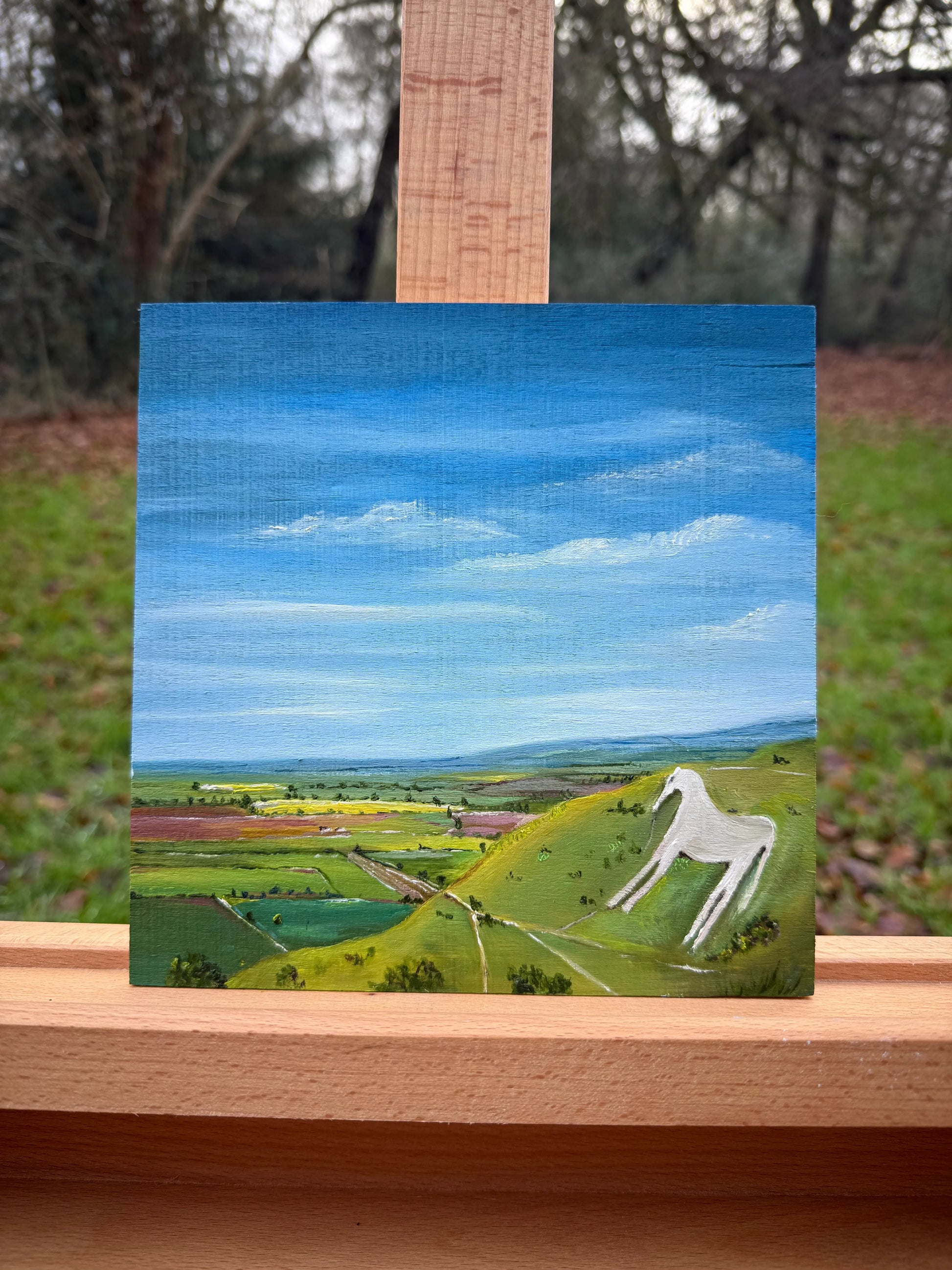 Oil painting of Westbury White Horse on green hillside under blue sky, countryside landscape